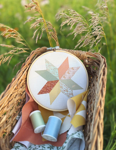 Buttercup Hill fabric collection from Sincerely Yours Kimberly. The quilt star fabrics is shown in a wildflower field at the golden hour in a wooden basket. The collection is about vintage farmhouse. Summer evenings in grandma's kitchen. The fabrics are available at Spoonflower.